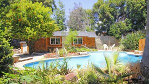 A backyard with a swimming pool, surrounded by trees and a stone wall. - Walk to Village & 5C's & Trader Joe's/Private Pool (Claremont)
