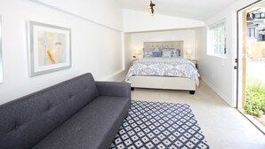 A modern bedroom with a grey sofa, patterned rug, and a bed with patterned bedding. - Walk to Village & 5C's & Trader Joe's/Private Pool (Claremont)