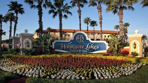 A sign for Westgate Lakes Resort & Spa surrounded by palm trees and a flower garden. - Mi Casa WestGate Lakes & spa Resort (Orlando)