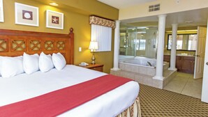 A hotel room with a large bed, a bathroom with a bathtub, and a view of the kitchen area. - Mi Casa WestGate Lakes & spa Resort (Orlando)