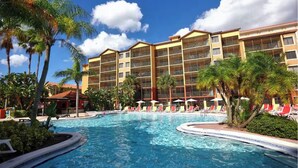 A hotel with a large pool surrounded by palm trees and lounge chairs. - Mi Casa WestGate Lakes & spa Resort (Orlando)