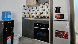 A compact kitchenette with a microwave, oven, and a water dispenser. - Studio Apartment Near JKIA and SGR (Syokimau)