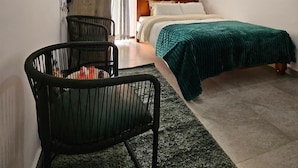 A bedroom with a bed, a desk, a chair, a TV mounted on the wall, and a window with curtains. - Studio Apartment Near JKIA and SGR (Syokimau)