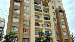A multi-story residential building with balconies, a brick facade, and a clear sky in the background. - Studio Apartment Near JKIA and SGR (Syokimau)
