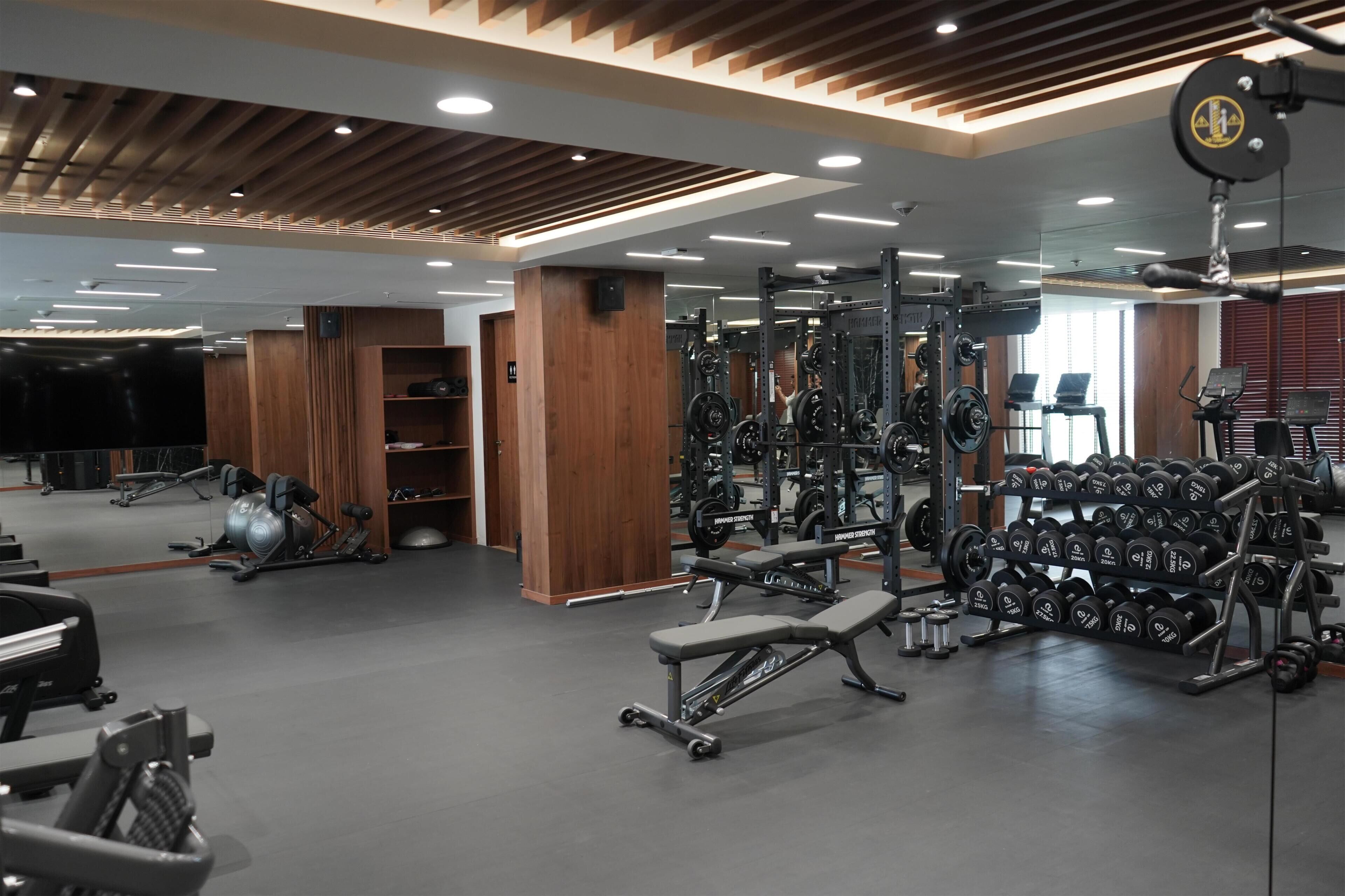 A gym with weightlifting equipment, benches, and a mirrored wall.