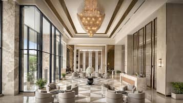 A spacious lobby with a large chandelier, marble flooring, and modern seating arrangements.