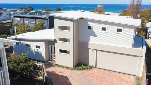 Un moderno edificio residencial de varios pisos con techo plano, paneles solares y garaje.