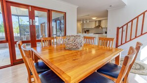 Un comedor con mesa y sillas de madera, un centro de mesa decorativo y vistas a la cocina y al patio exterior.
