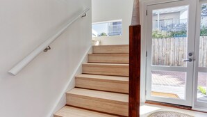 Una escalera de madera con barandilla blanca que lleva a una puerta de cristal.