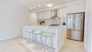 Una cocina moderna con una isla central, electrodomésticos de acero inoxidable y armarios blancos.