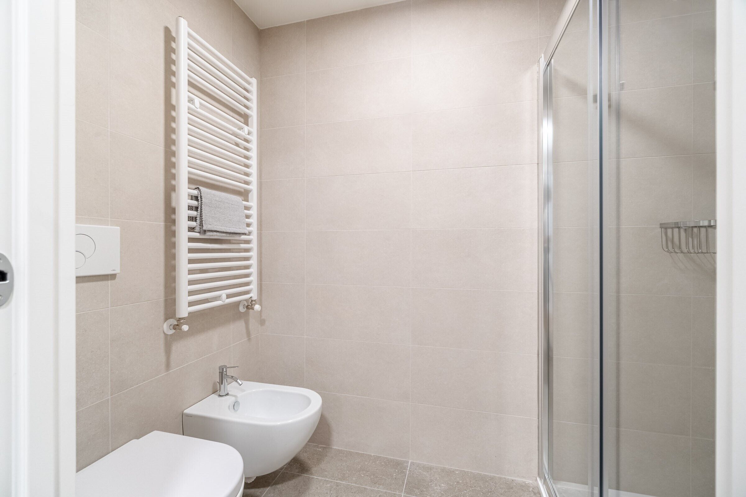 A bathroom with a toilet, bidet, and a glass shower enclosure.