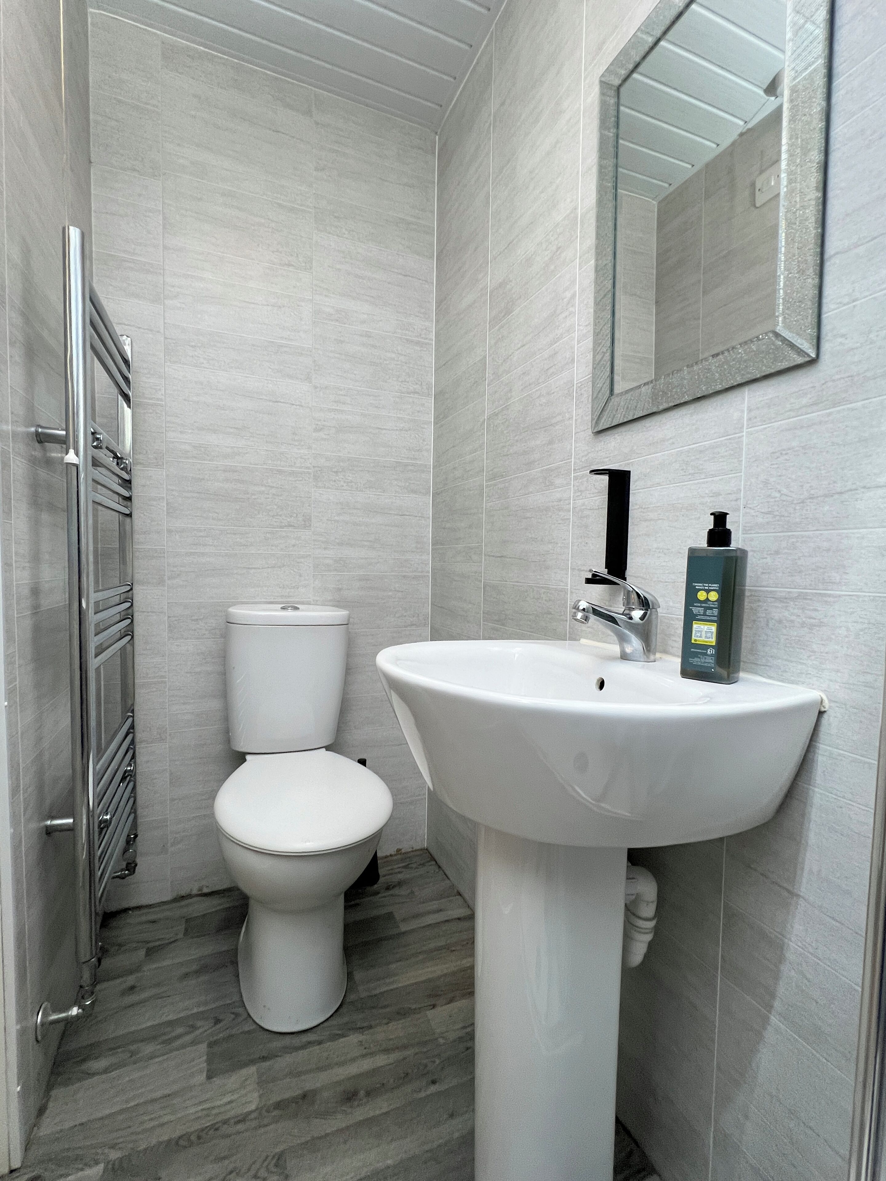 A modern bathroom with a white toilet, a pedestal sink, and a mirror above the sink.
