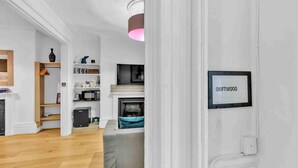Een moderne woonkamer met een grijze bank, houten vloer en een open haard.