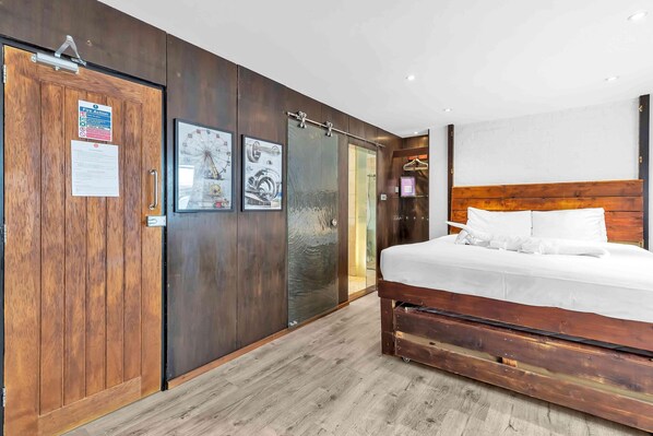 A bedroom with a wooden bed, a sliding door, and a glass door leading to a bathroom.