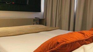 A hotel room with a bed, a TV mounted on the wall, and a window with curtains. - Flat Studio Everest: Your Accommodation in Boa Viagem (Recife)