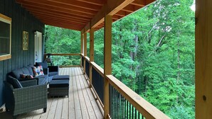 Eine überdachte Veranda mit Blick auf einen Wald.