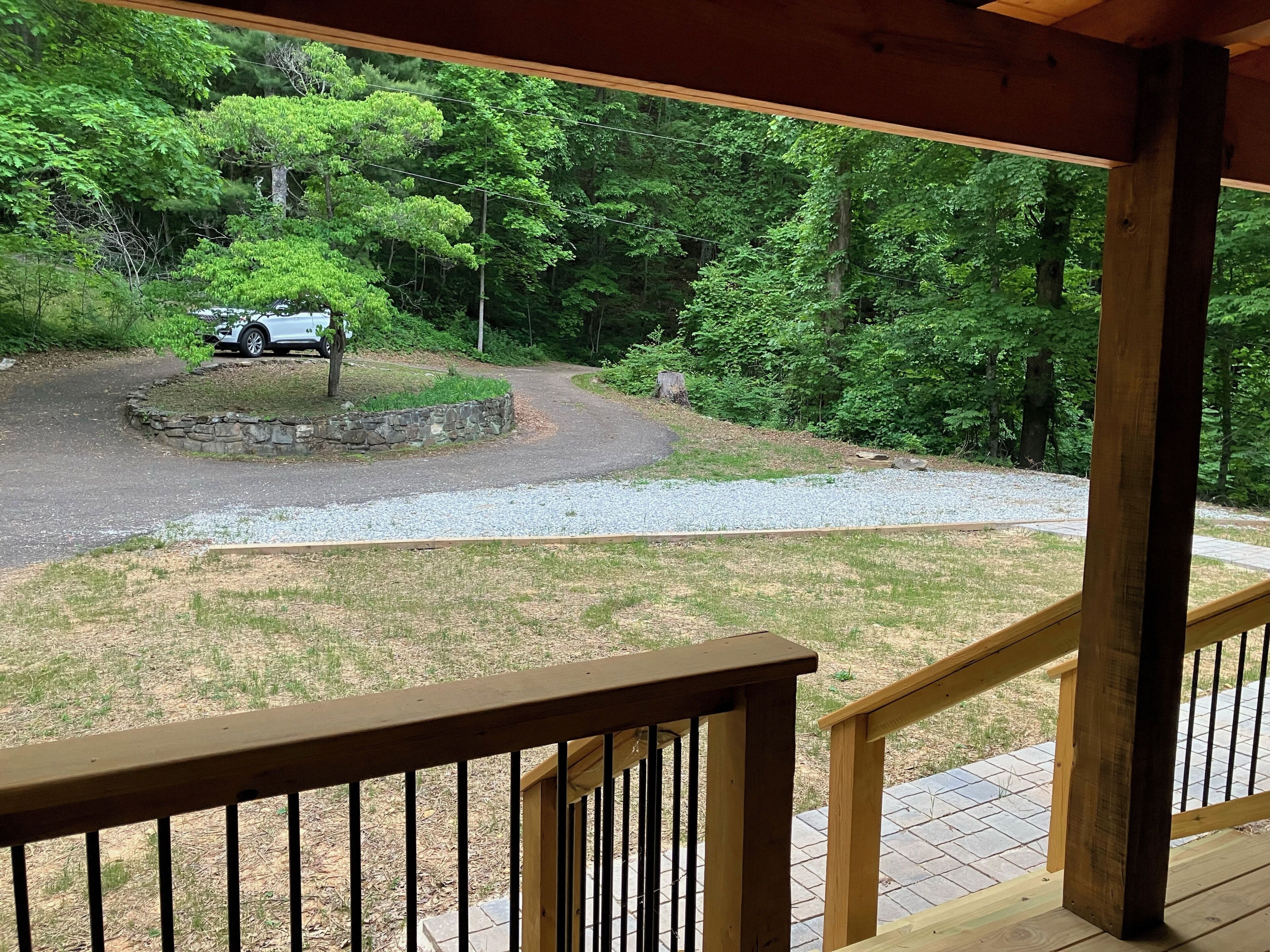 A wooden deck with a stone pathway leading to a driveway.