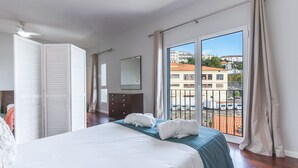 Ein Schlafzimmer mit Bett, Schminktisch, Spiegel und Blick ins Freie.