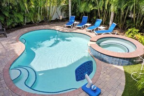 A swimming pool with a hot tub, surrounded by lounge chairs and palm trees. - 2-Min walk to beach, Pool, Hot Tub, Putting Green! (Holmes Beach)
