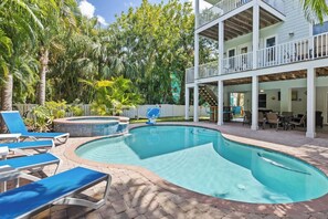 A swimming pool with lounge chairs, a hot tub, and a covered patio area with outdoor furniture.