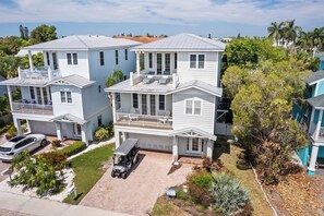 A two-story residential building with a covered porch, a garage, and a driveway. - 2-Min walk to beach, Pool, Hot Tub, Putting Green! (Holmes Beach)