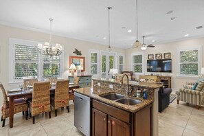 A spacious kitchen with granite countertops, a built-in dishwasher, and a dining area with wicker chairs.