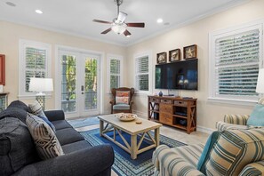 Un salon comprenant un canapé, un fauteuil, une table basse, un téléviseur et des objets de décoration.