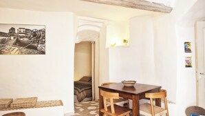 A cozy room with a wooden dining table, a sofa, and a wall-mounted picture. - Sublime atypical apartment with terrace in the heart of ERBALUNGA (Brando)