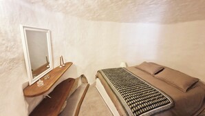 A small, cozy bedroom with a single bed, a wooden nightstand, a mirror, and a bedside table with candles. - Sublime atypical apartment with terrace in the heart of ERBALUNGA (Brando)
