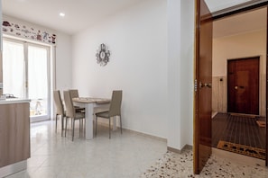 Un coin repas avec une table et des chaises, une horloge murale et une porte donnant sur une autre pièce.
