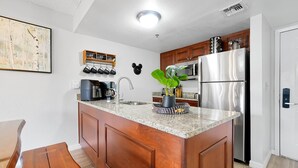 A kitchen with wooden cabinets, a stainless steel refrigerator, a microwave, and a sink. - Parkside on I-Drive - Stay near ALL theme parks (Kissimmee)