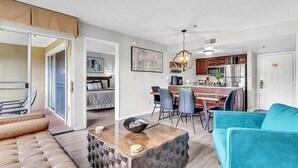 A modern living room with a sofa, a dining area with chairs, and a kitchen in the background. - Parkside on I-Drive - Stay near ALL theme parks (Kissimmee)