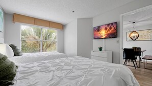 A modern bedroom with a large bed, a TV, and a desk area. - Parkside on I-Drive - Stay near ALL theme parks (Kissimmee)