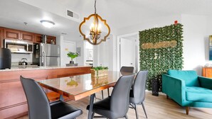 A modern kitchen with a stainless steel refrigerator, wooden cabinets, and a glass dining table with black chairs. - Parkside on I-Drive - Stay near ALL theme parks (Kissimmee)