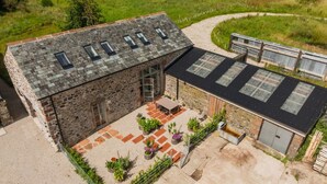 A stone building with a patio area, a covered outdoor seating area, and a fenced garden.