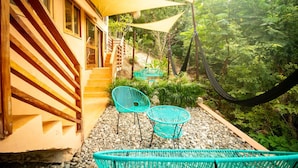 A wooden staircase leading to a building with a yellow exterior, outdoor seating area with turquoise chairs, and a hammock. - 2 Room Loft w/ patio, parking, kitchen (Mazunte)