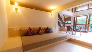 A modern living room with a sofa, colorful cushions, a staircase, and a dining area with chairs. - 2 Room Loft w/ patio, parking, kitchen (Mazunte)
