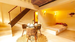 Une chambre à coucher moderne avec un lit, une table à manger avec des chaises, un escalier et un luminaire fixé au mur.
