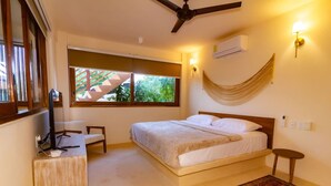 Une chambre avec un lit, un bureau, une chaise, un ventilateur de plafond, une fenêtre donnant sur un beau paysage, un climatiseur et un tapis.