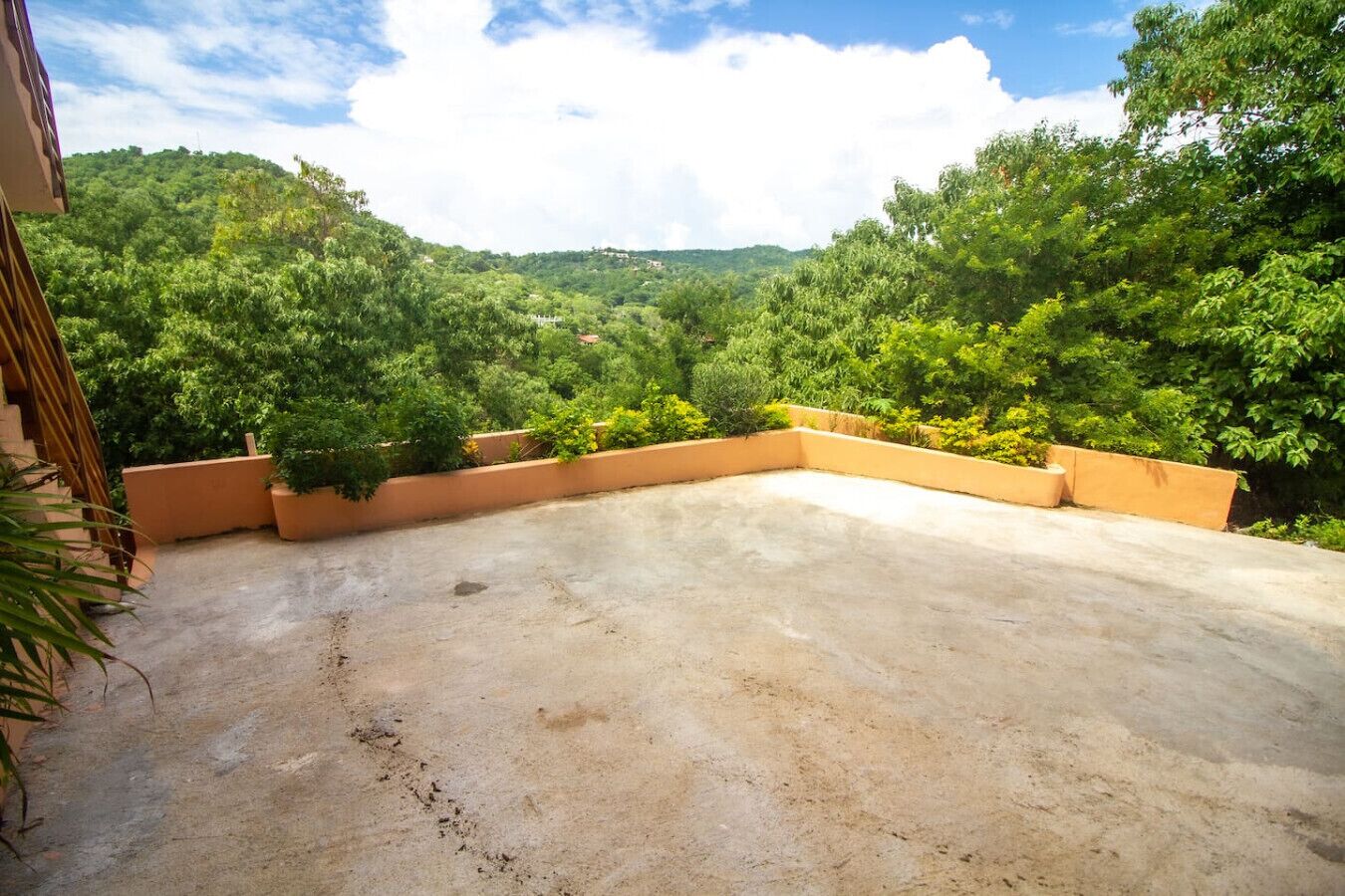 Une terrasse sur le toit, dotée d’un sol en béton et offrant une vue sur un paysage verdoyant et luxuriant.