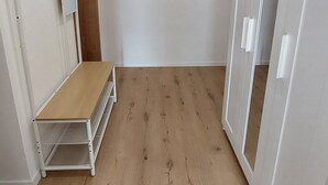 Una stanza con pavimento in legno, pareti bianche, una panca e un armadio.
