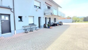Un edificio con facciata piatta, una porta, una panchina e un tavolo all'esterno.