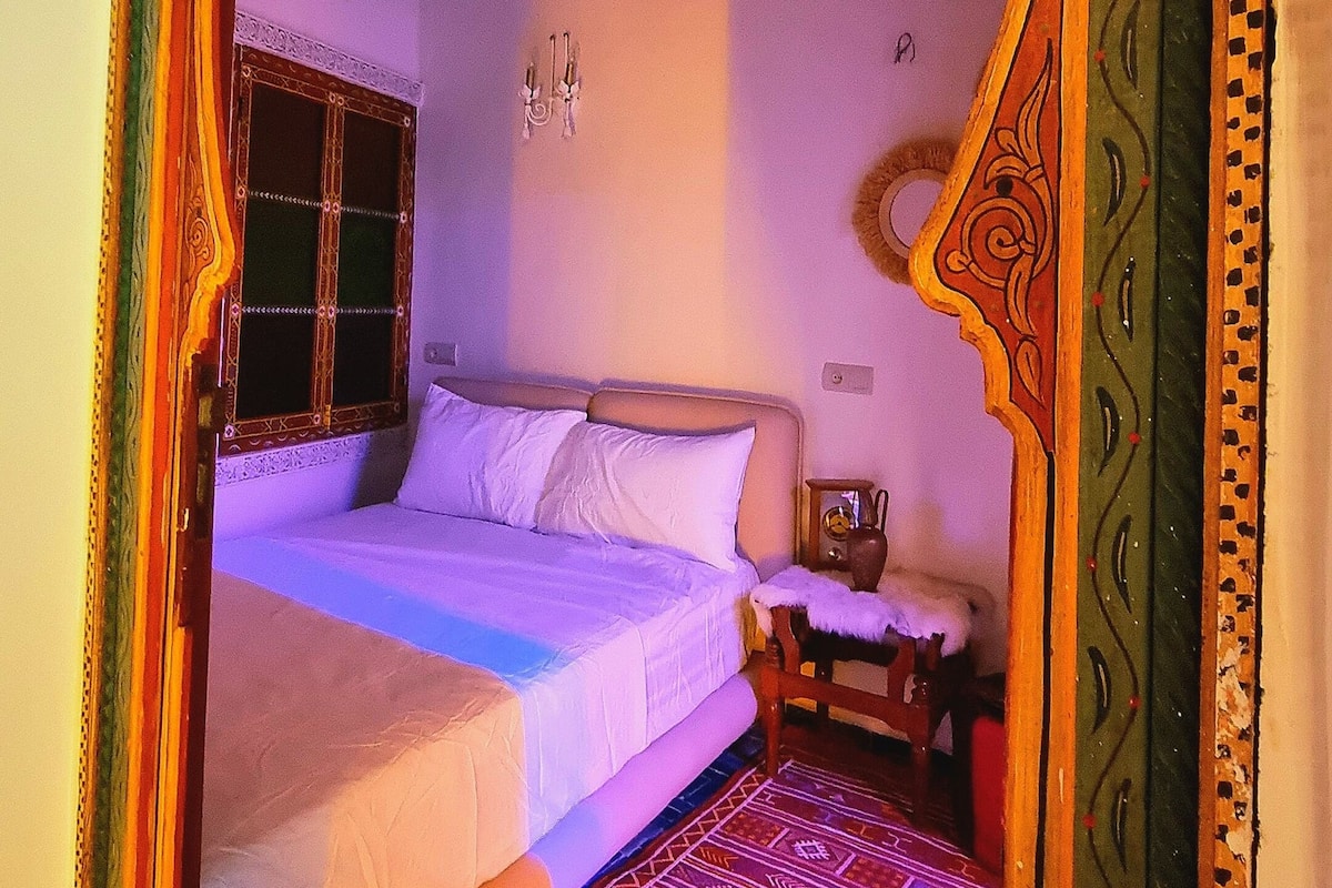 Una habitación con cama, una mesita y un arco decorativo.