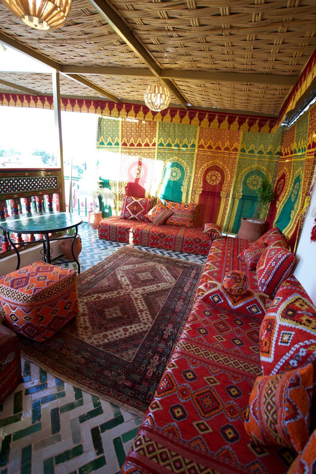 A traditional room with patterned textiles, a woven ceiling, and a patterned floor.