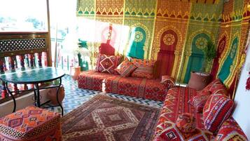 A traditional room with patterned textiles, a woven ceiling, and a patterned floor.