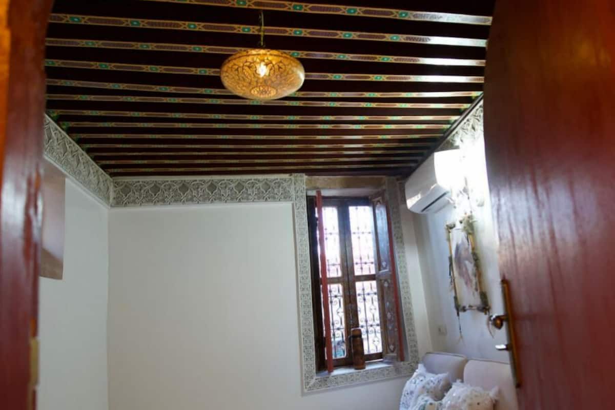 Una habitación pequeña y acogedora con cama, ventana y techo decorado.