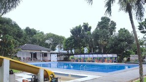 A swimming pool with a covered area, a small building, and a grassy area with trees. - PAVO RESORT (Citaringgul)