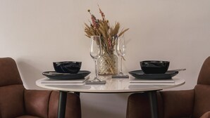 Et spisebord med to sorte skåle, en klar glasvase med tørrede blomster og to vinglas.