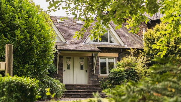 A stone house with a white door, a small porch, and a garden. - A cosy, base for two in Windermere, perfect for laid-back Lake District getaways. (Windermere)