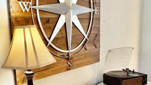 A room with a wooden wall decor, a lamp, a record player, and a small table with a Wi-Fi sign. - Charming Country Getaway in Reilly Springs (Sulphur Springs)